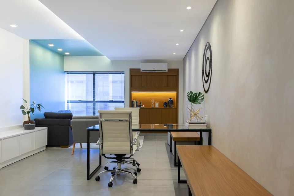 Sala de atendimento da Orbis Psicologia com mesa, área de estar e marcenaria iluminada